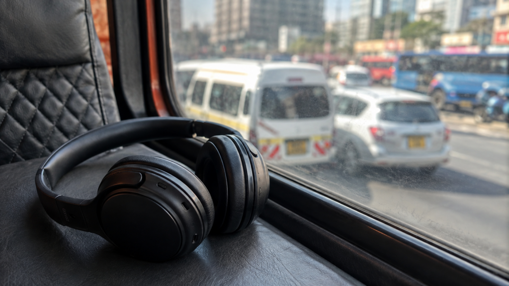 Headphones resting by a matatu window with blurred Nairobi traffic